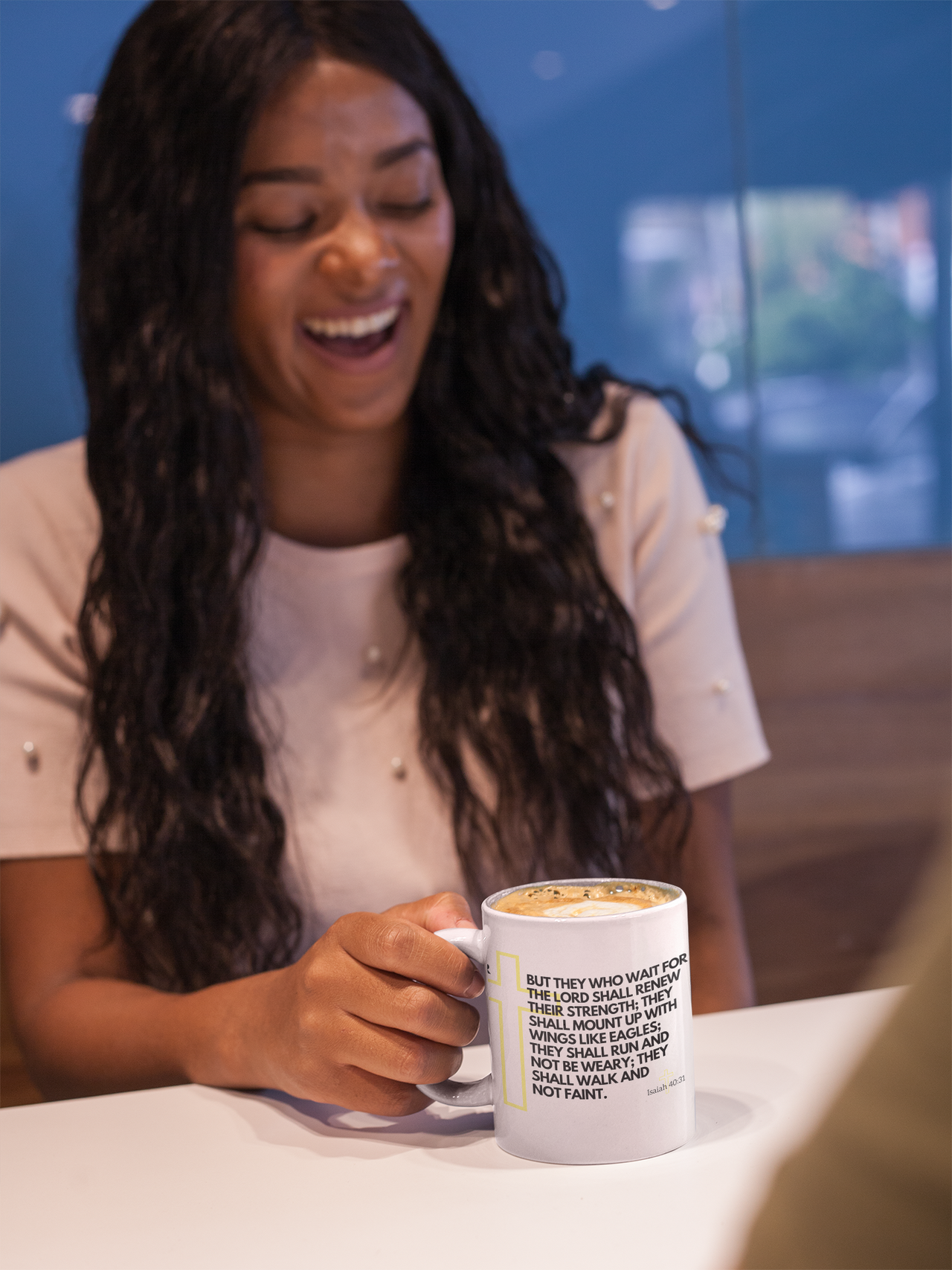 a woman sitting at a table holding a coffee mug