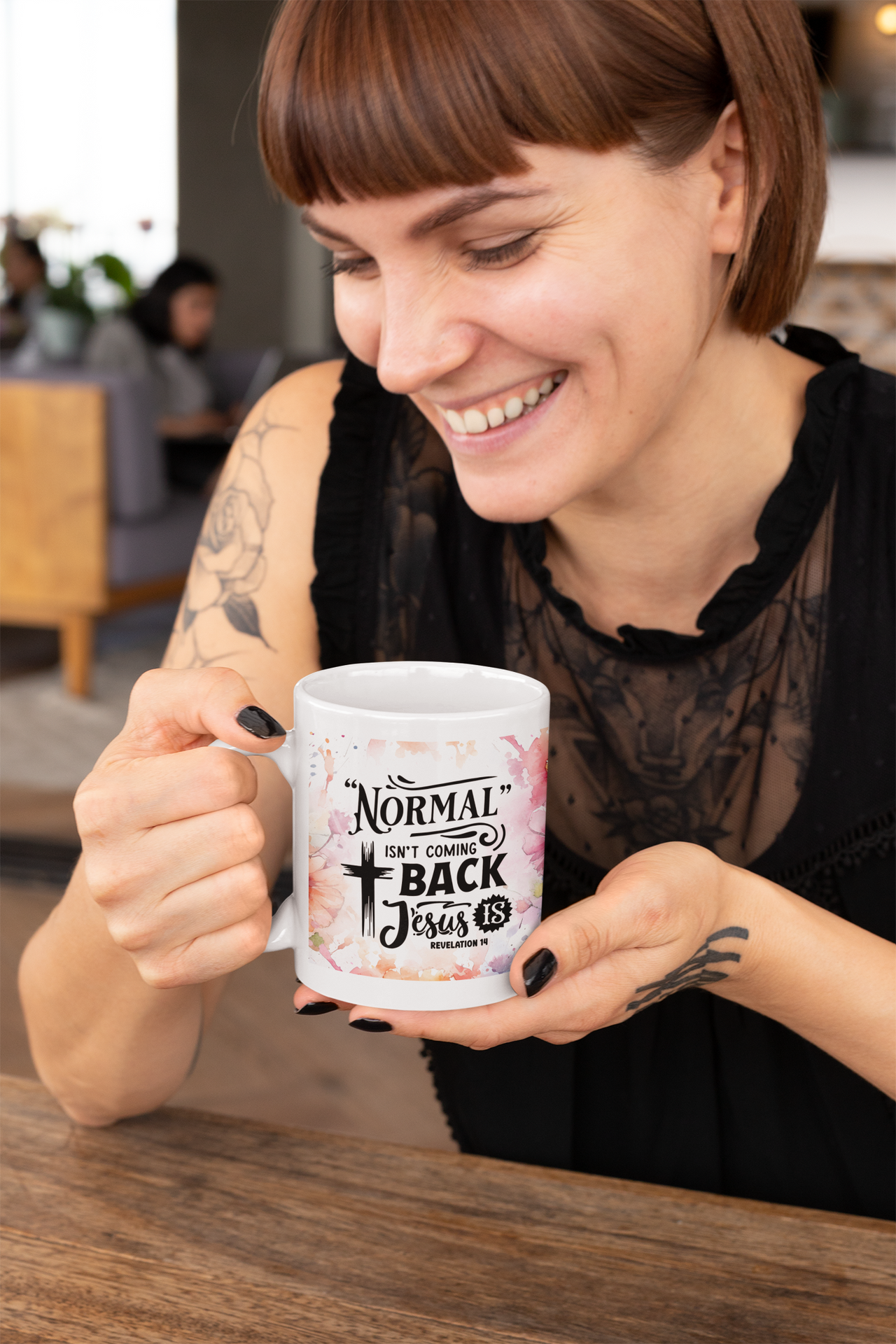 a woman sitting at a table holding a coffee mug