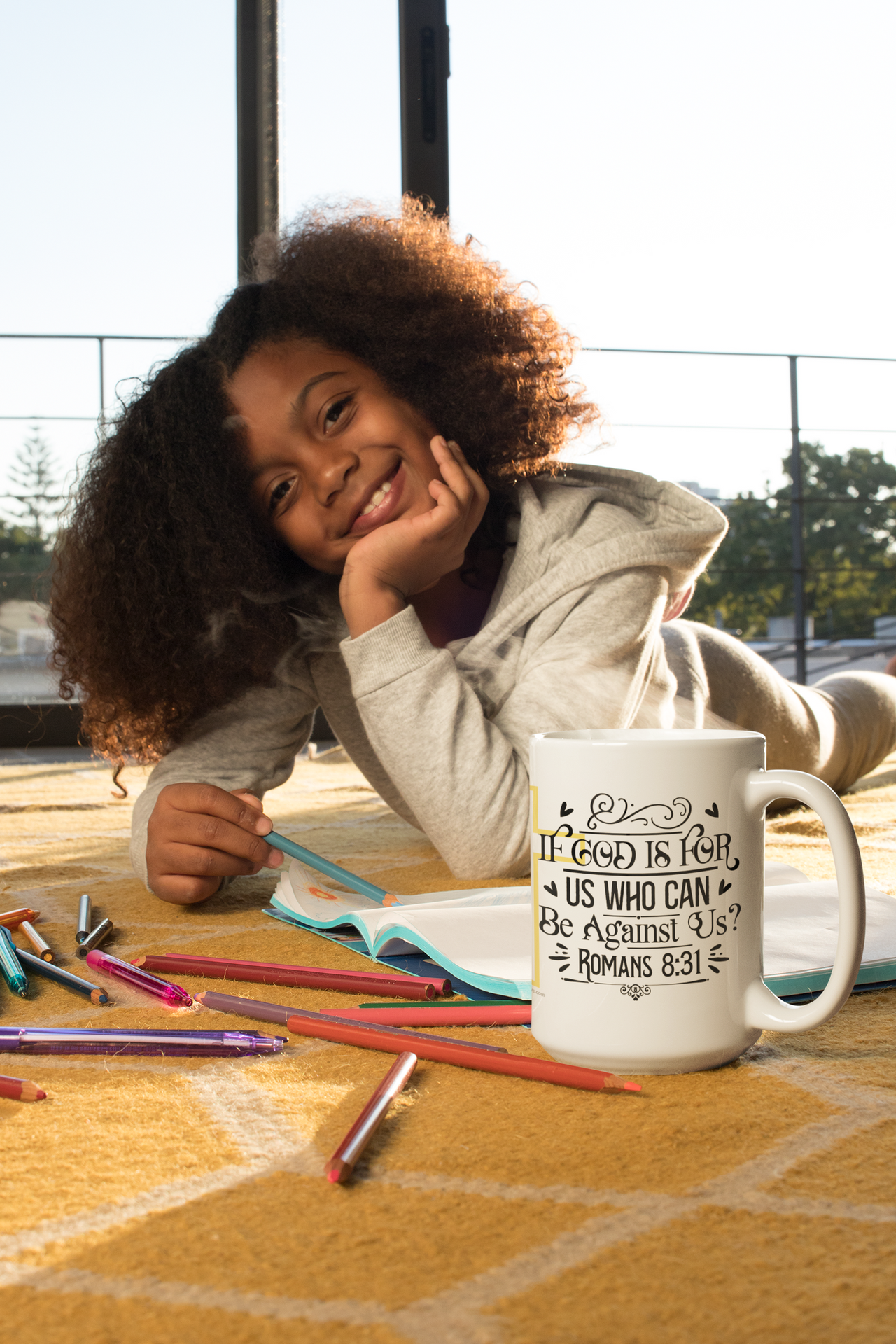 a little girl laying on the ground with a coffee mug