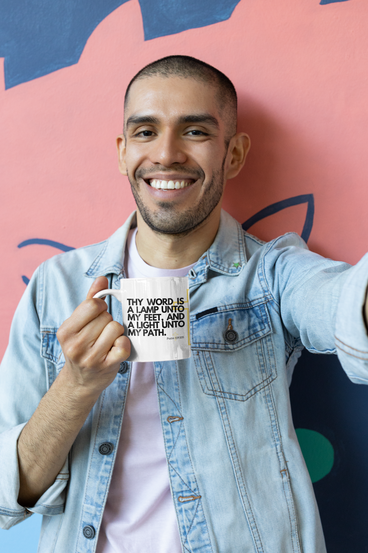 a man holding a coffee mug in front of a wall