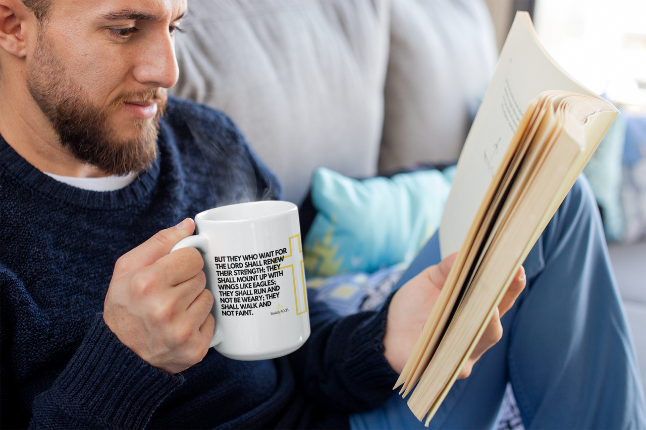 a man sitting on a couch holding a book and a coffee mug