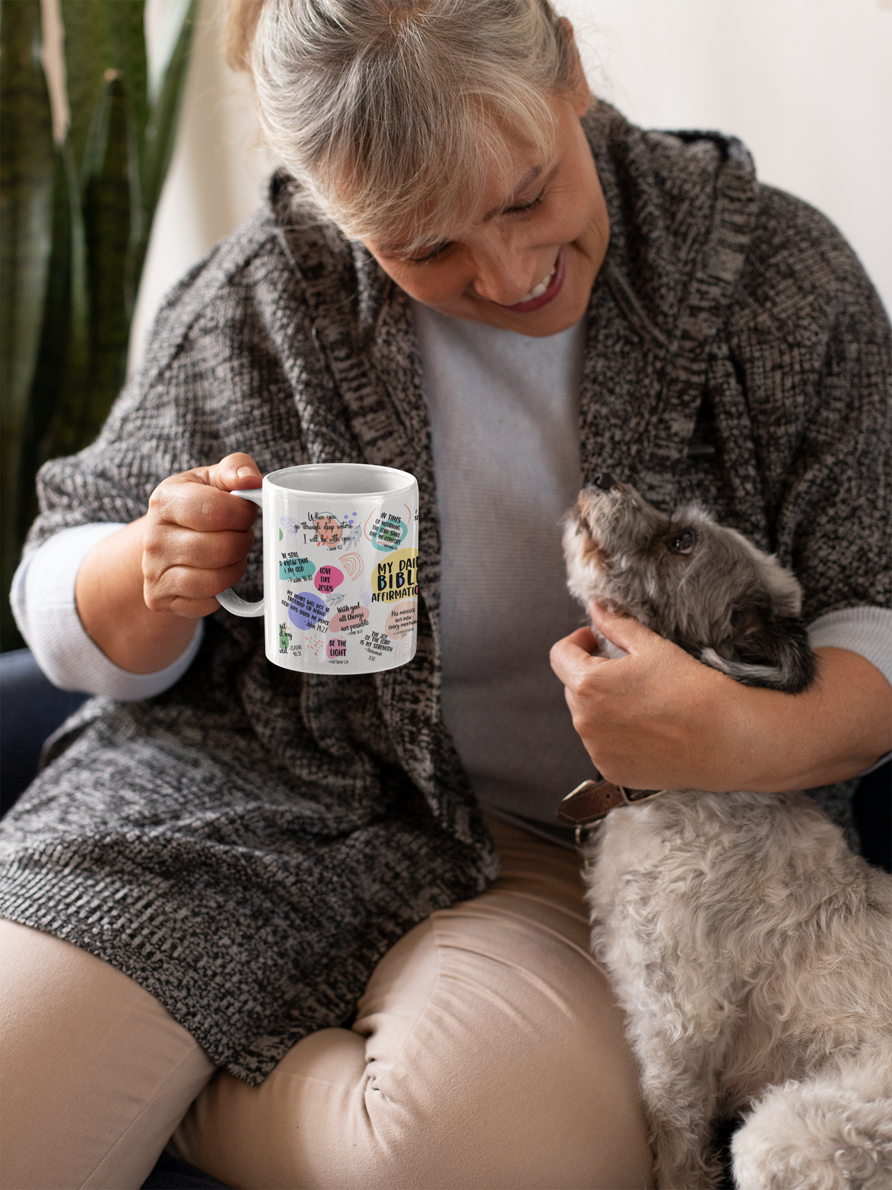 a woman sitting on a couch holding a dog and holding a coffee mug