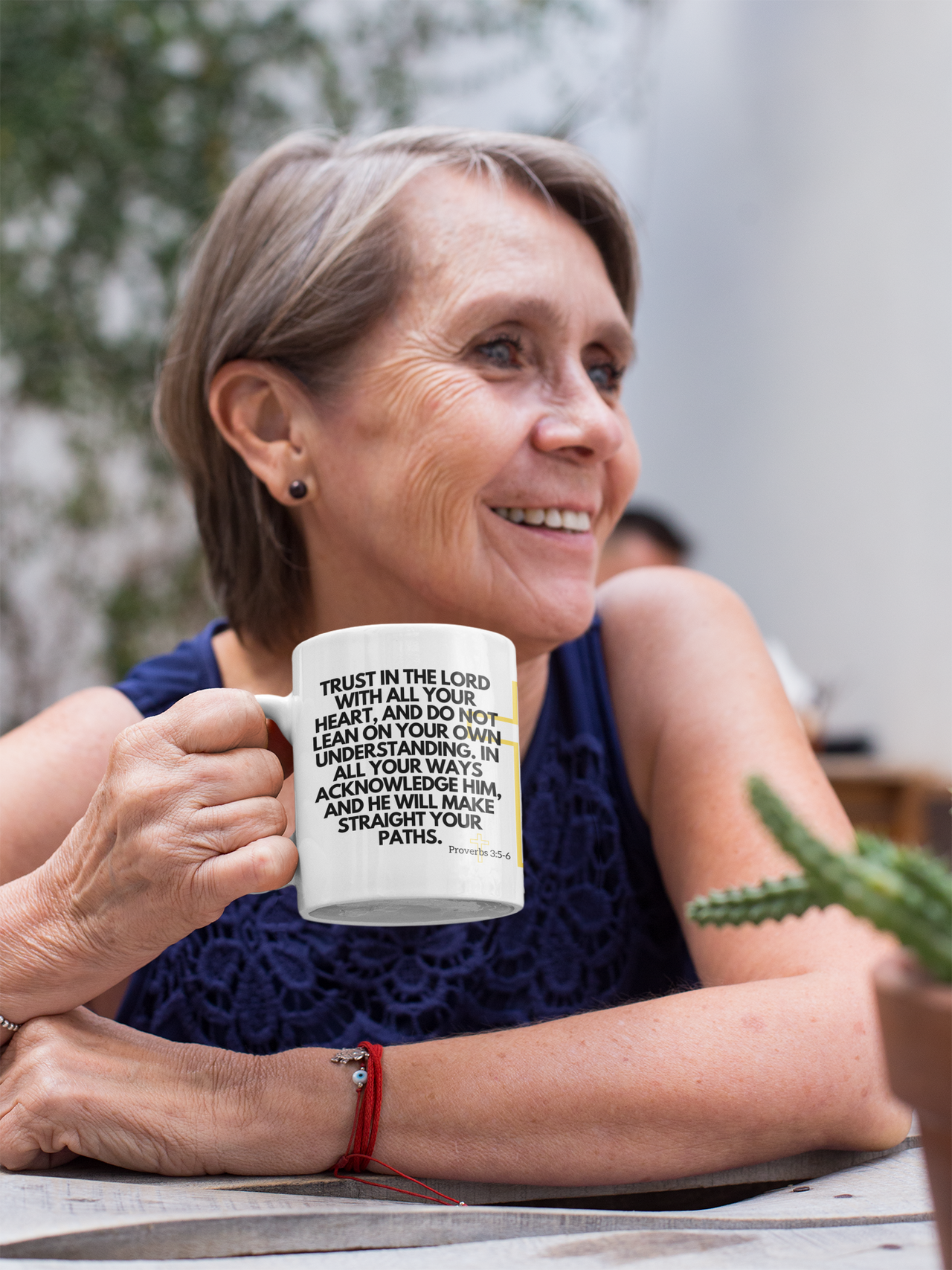 a woman sitting at a table holding a coffee mug