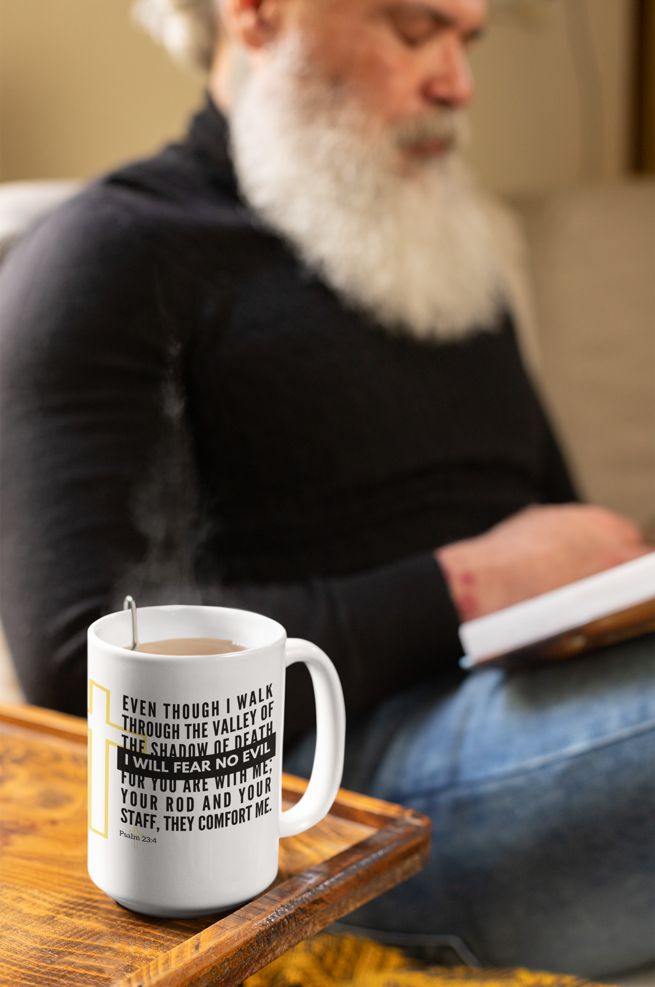 a man sitting on a couch with a book and a cup of coffee