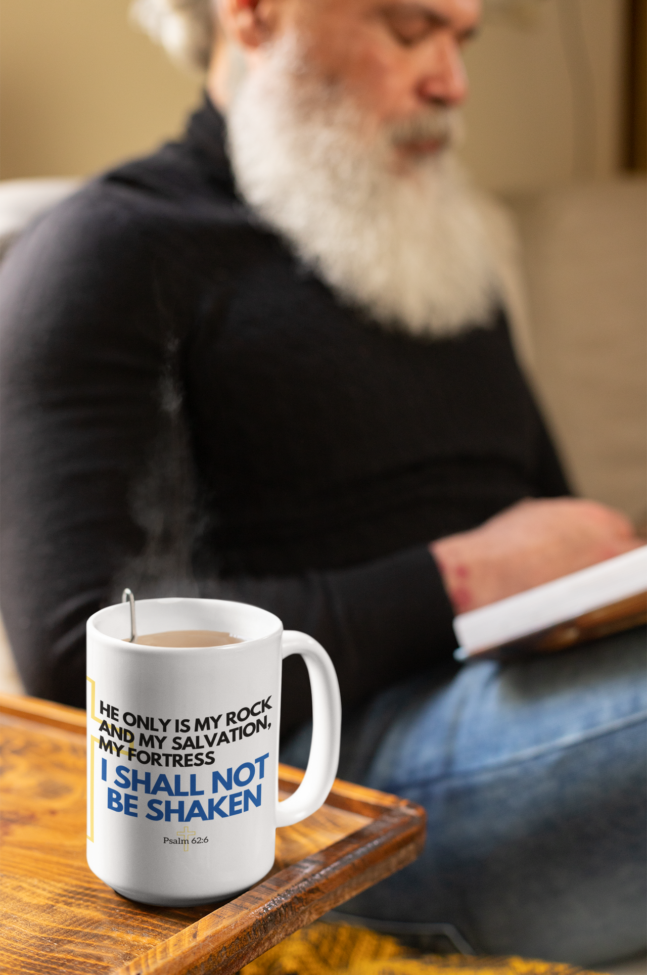 a man sitting on a couch with a book and a coffee mug