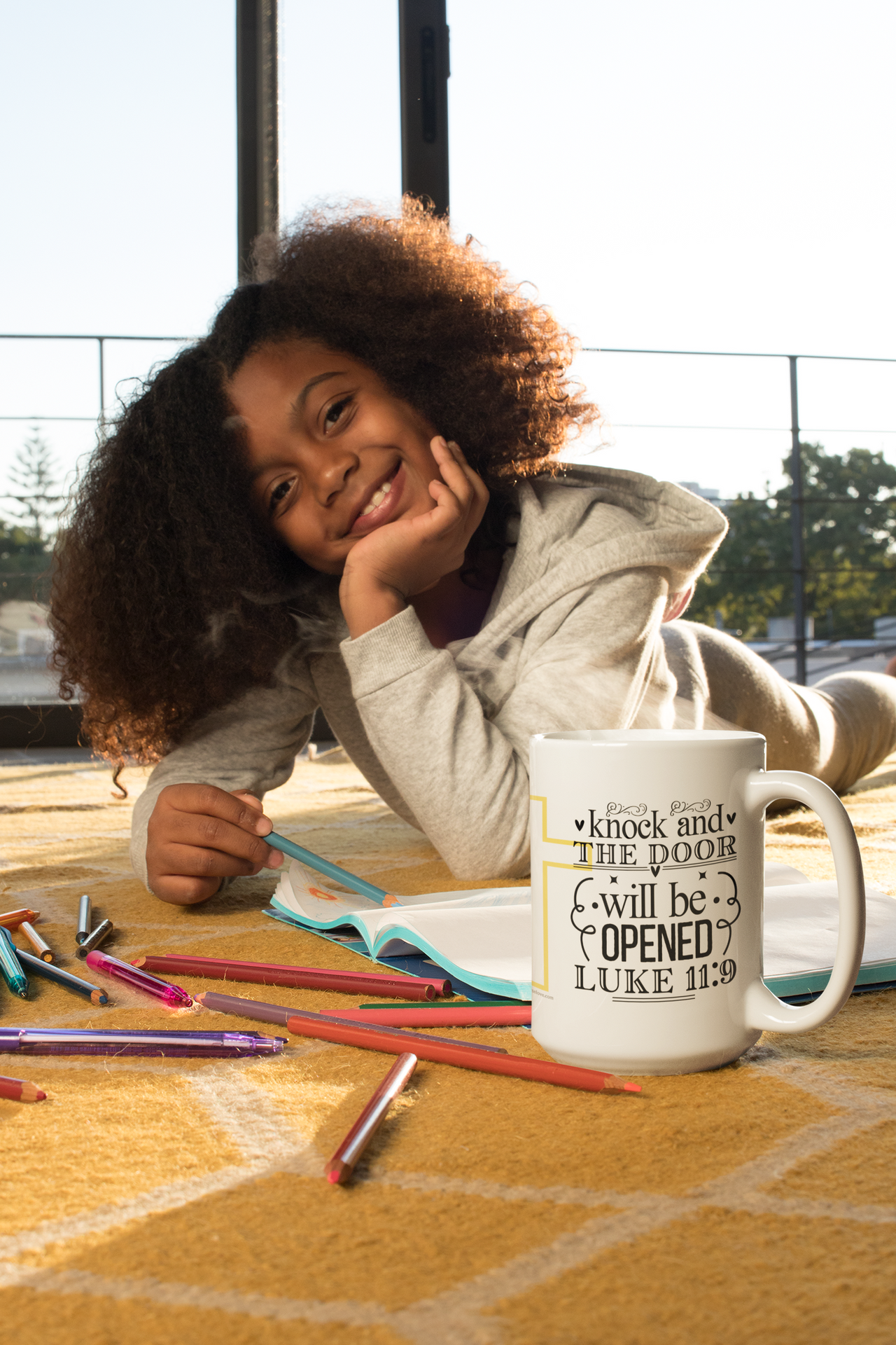 a little girl laying on the floor with a coffee mug