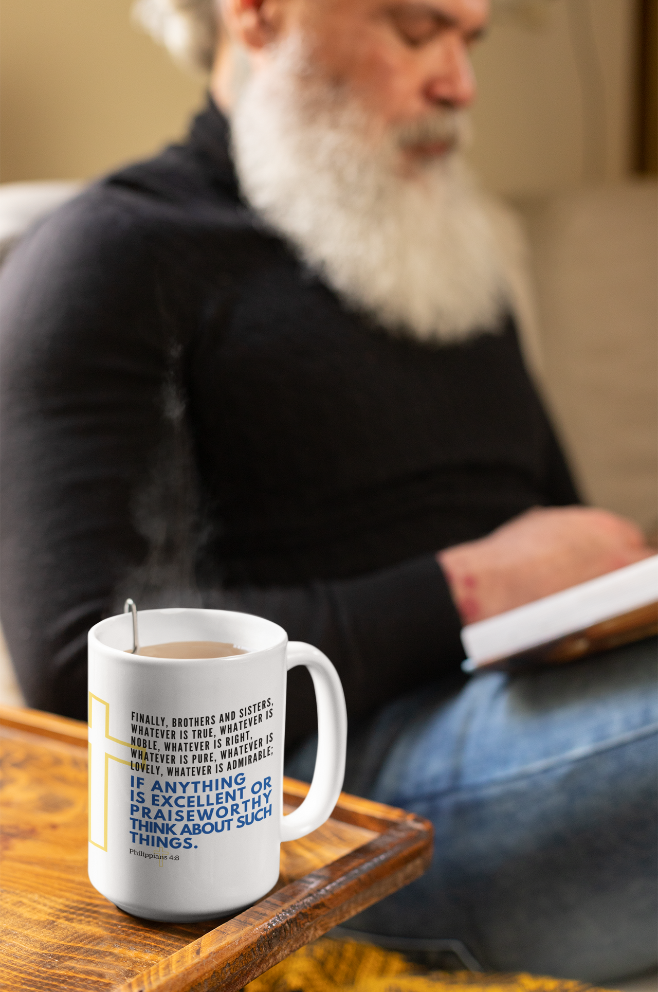 a man sitting on a couch with a book and a cup of coffee