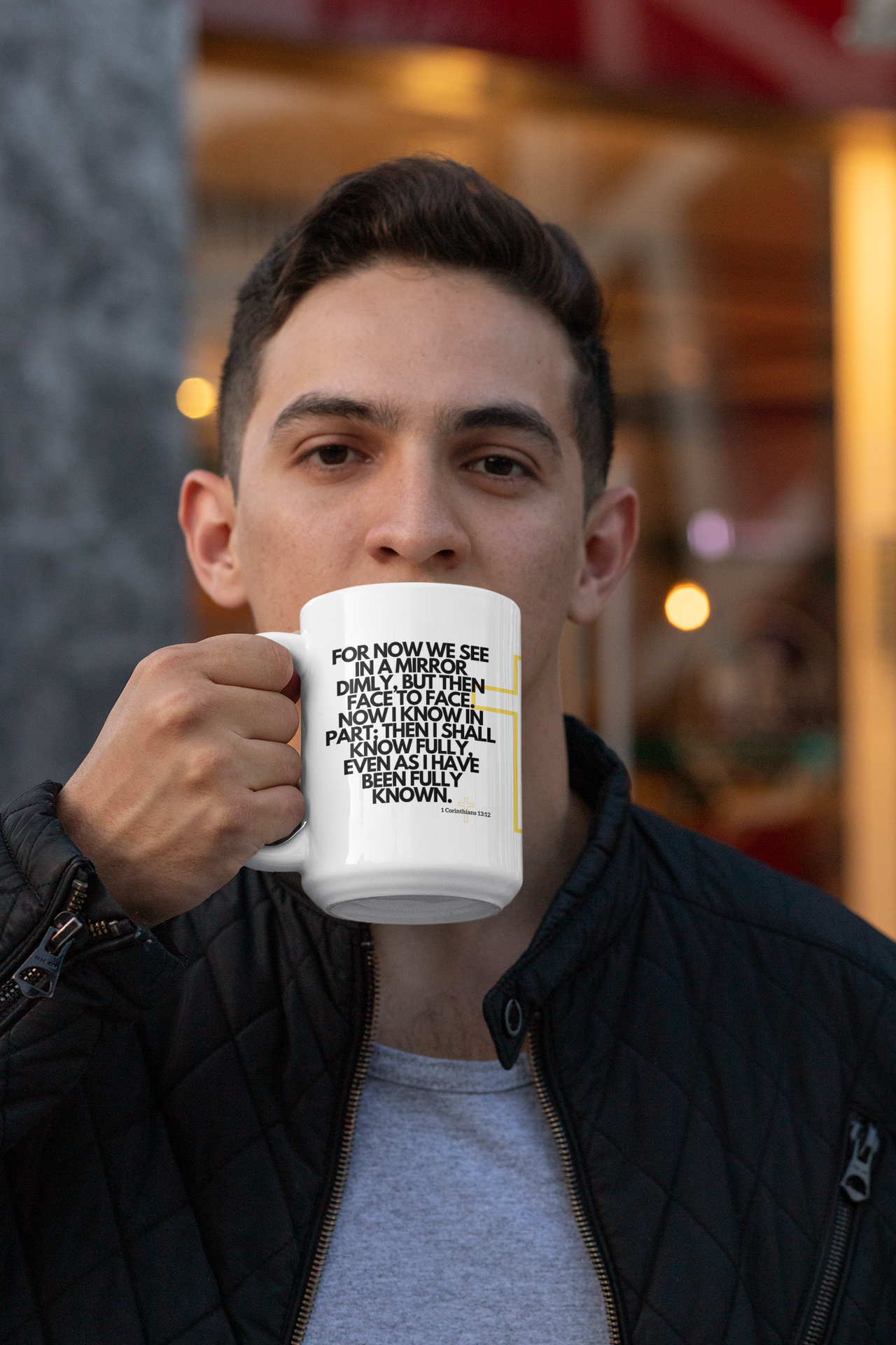 a man holding a white coffee mug with a q on it