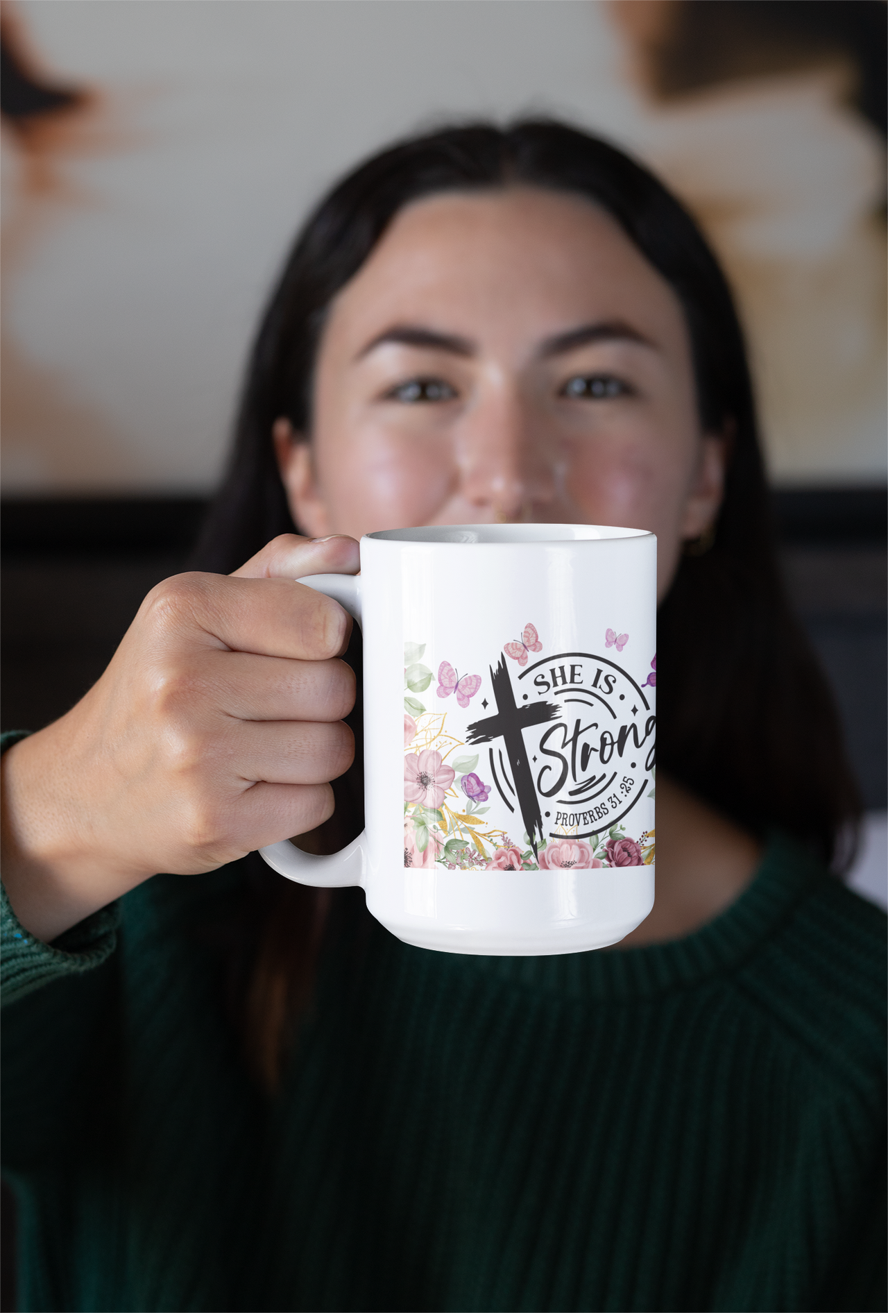 a woman holding a coffee mug with a cross on it