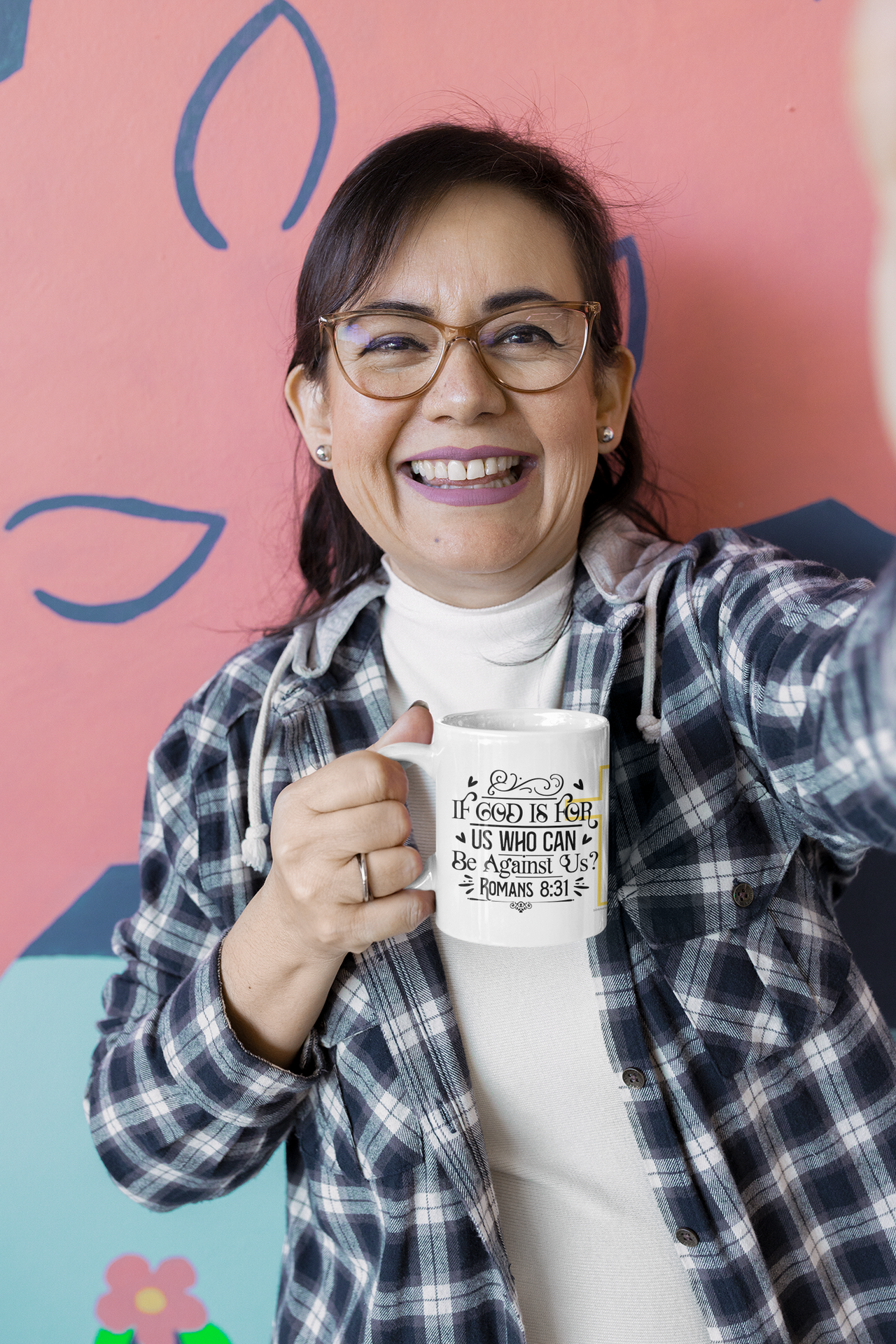 a woman holding a coffee mug in front of a wall