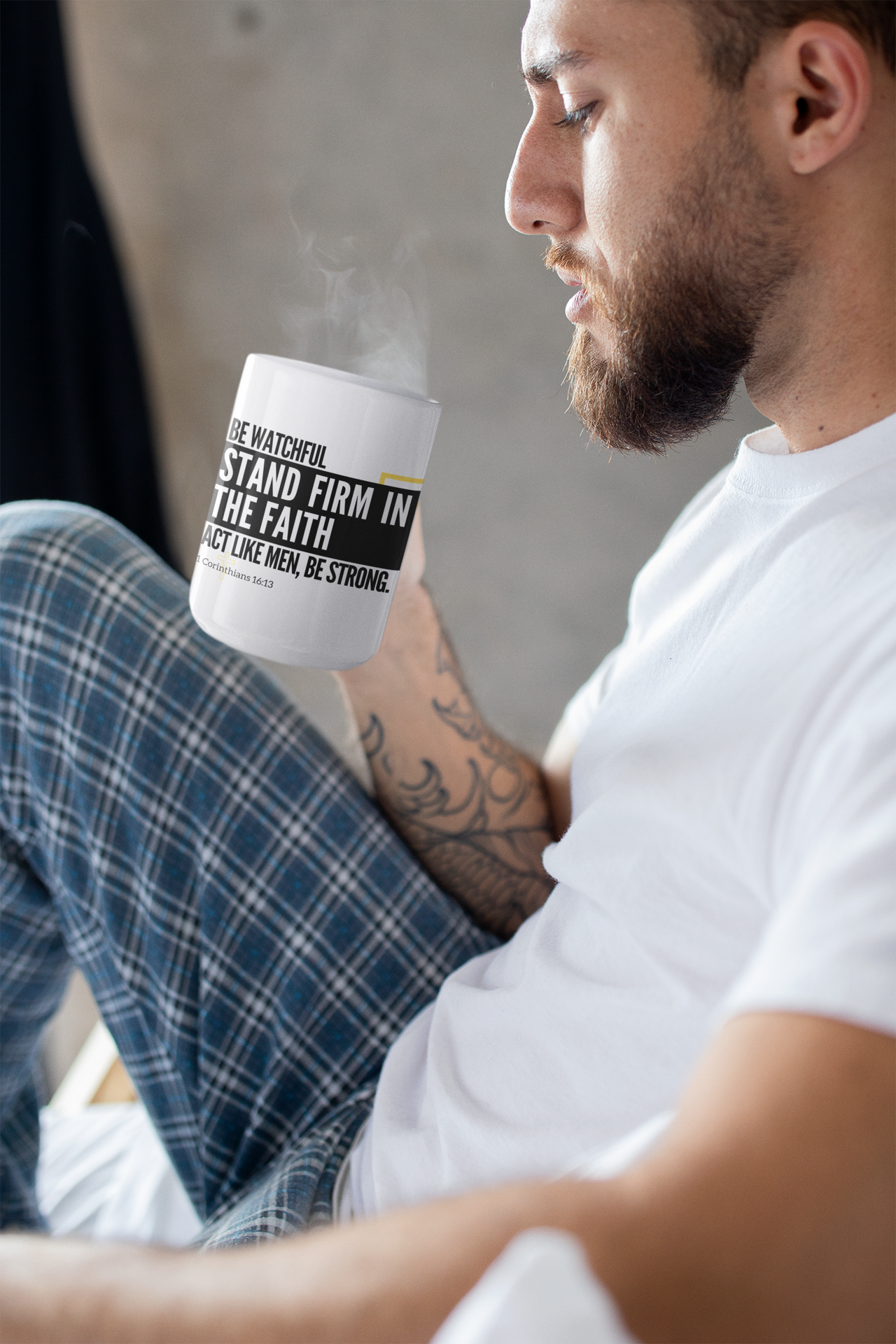 a man sitting on a bed holding a cup of coffee