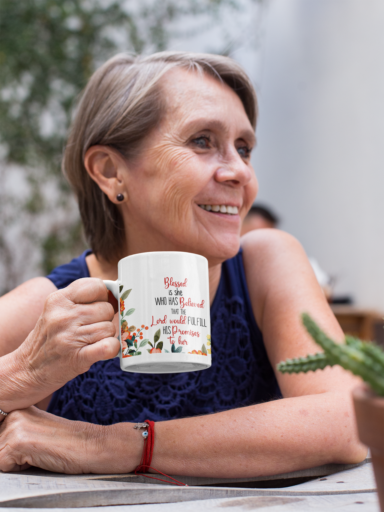 a woman sitting at a table holding a coffee mug