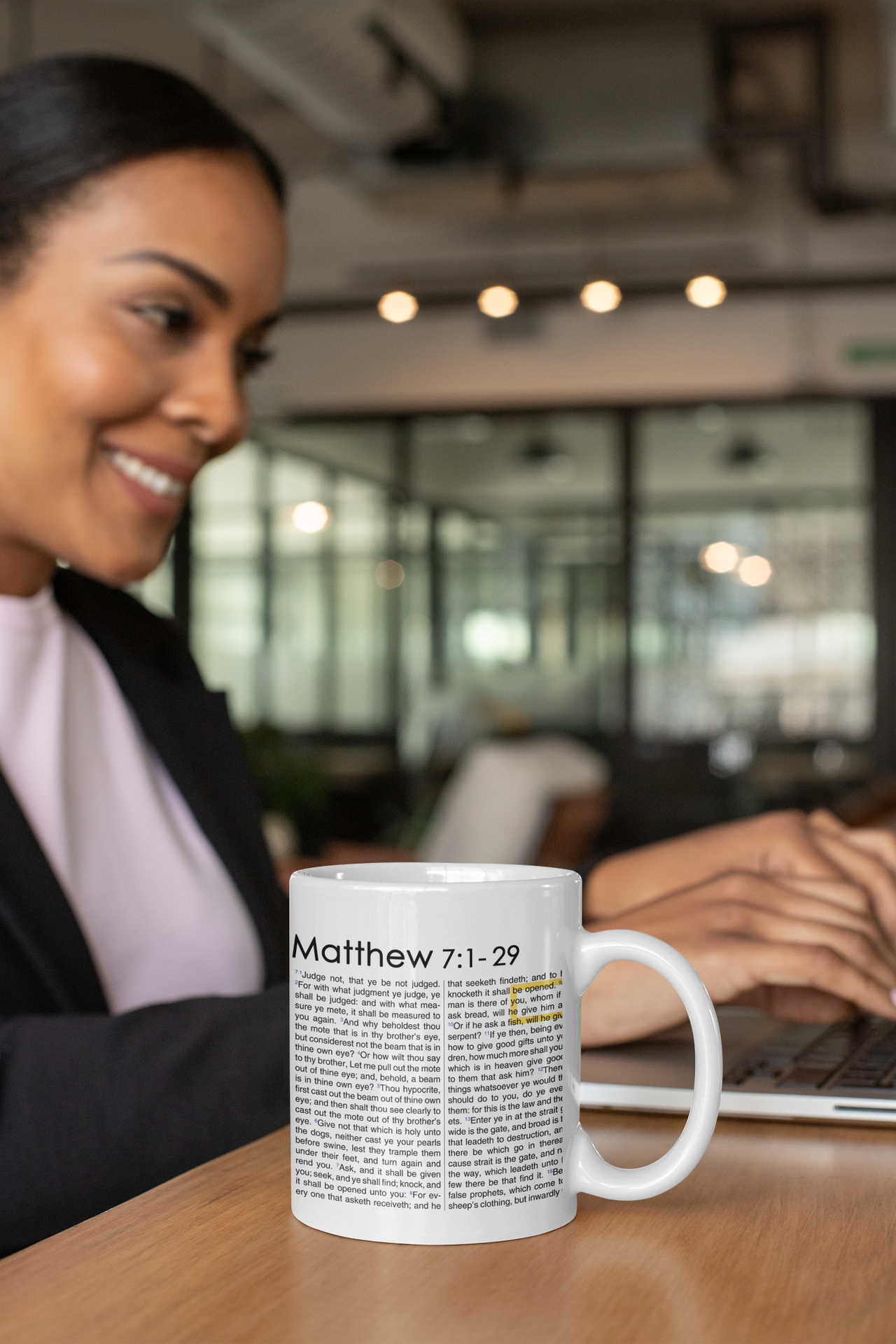 a woman sitting at a table with a coffee mug in front of her