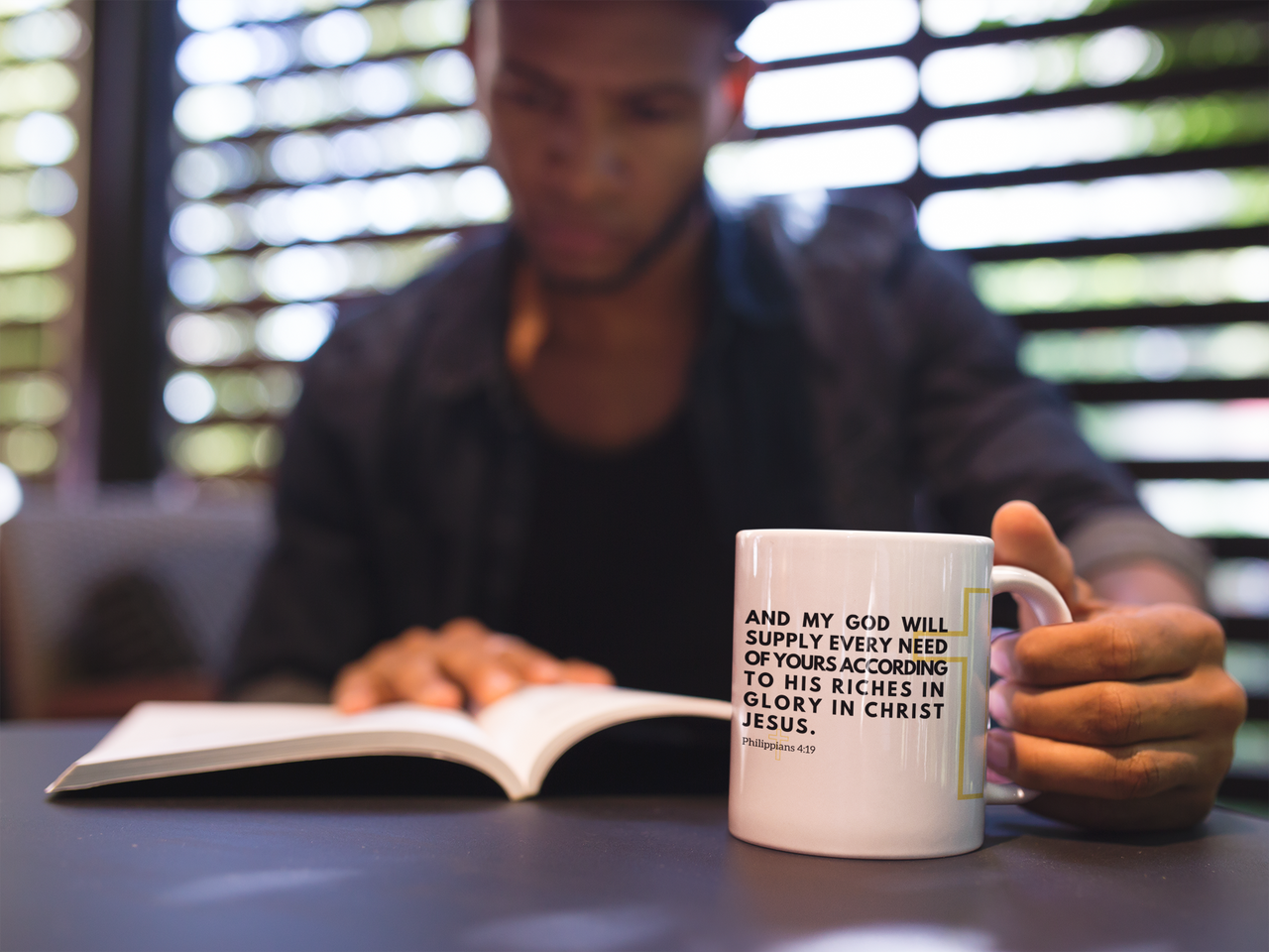 a man reading a book and holding a coffee mug