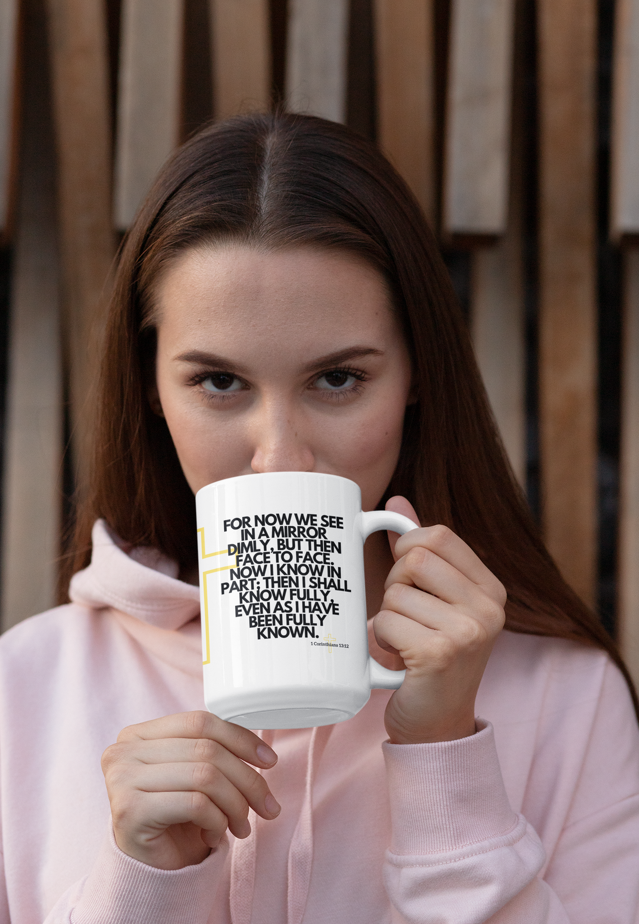 a woman in a pink hoodie holding a coffee mug